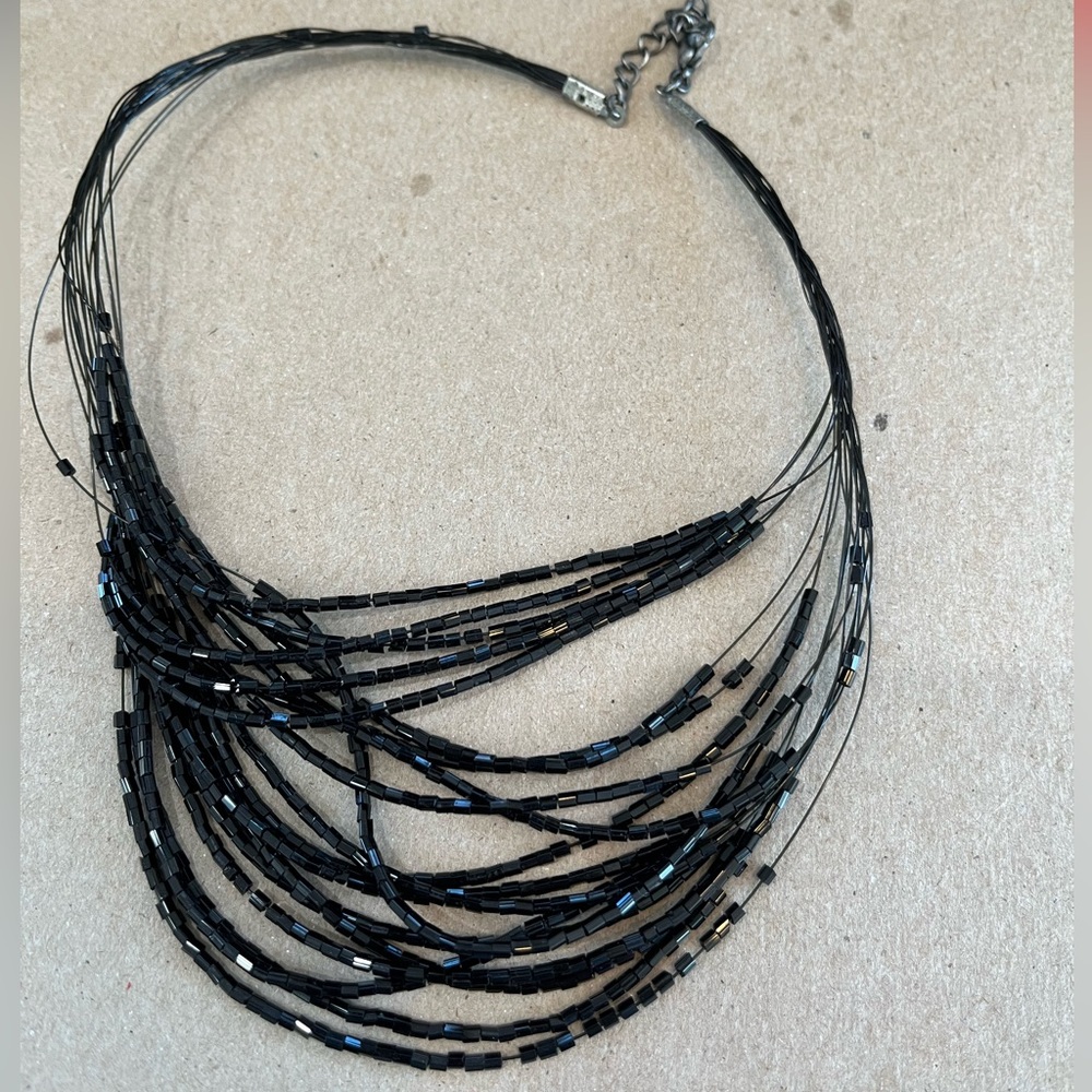 Black multi strand beaded adjustable necklace on black strand wire.